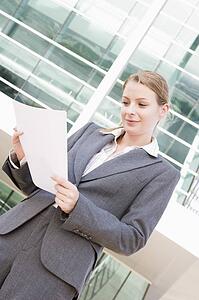 Businesswoman standing outdoors reading paperwork