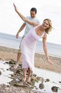 Couple at the beach walking on stones and smiling