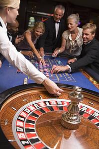 Group of people in casino playing roulette and smiling (selective focus)