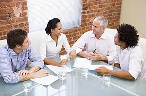 Four businesspeople in boardroom smiling