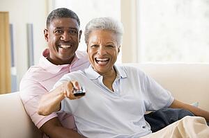 Couple in living room using remote control smiling