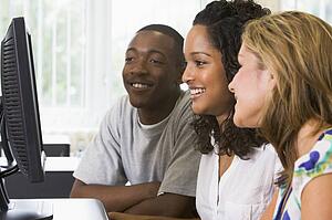 Three people sitting at a computer terminal (high key)