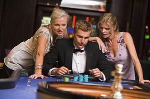 Three people in casino playing roulette smiling (selective focus)