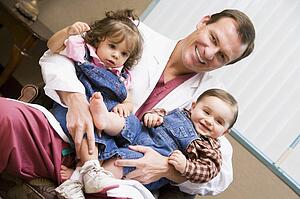 Doctor sitting with two IVF children smiling
