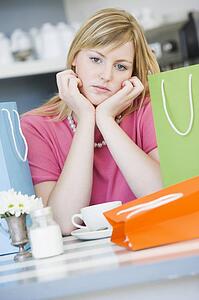 Young woman sitting at a table taking a break from shopping and drinking tea