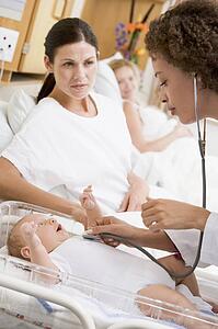 Doctor checking baby's heartbeat with new mother watching