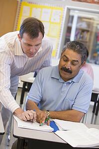 Adult student in class with teacher helping him