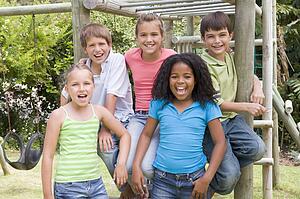 Five young friends at a playground smiling