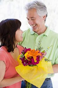 Husband and wife holding flowers and smiling
