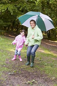 Father and daughter outdoors with umbrella smiling
