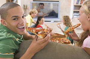 Teenagers Hanging Out In Front Of Television Eating Pizza 