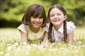 Two sisters lying outdoors smiling