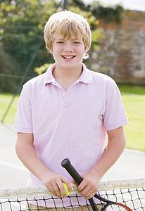 Young boy with racket on tennis court smiling