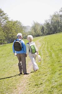 Couple walking on path in park holding hands