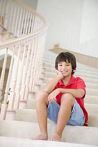 Young Boy Sitting On A Stairwell At Home