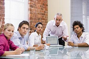 Five businesspeople in boardroom with laptop
