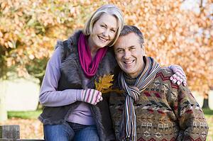 Couple outdoors in park by fence smiling (selective focus)
