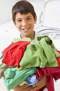 Young Boy Holding A Pile Of Laundry