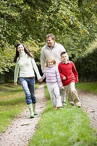 Family walking on path outdoors smiling (selective focus)