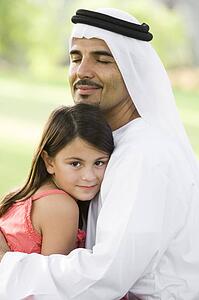 Man and young girl outdoors in park embracing and smiling (selective focus)