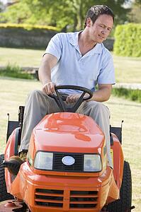 Man outdoors driving lawnmower