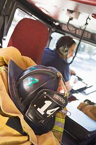 Firefighting gear in the back of a fire engine with fireman in background (selective focus)