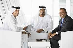 Three businessmen indoors with a laptop smiling (high key/selective focus)