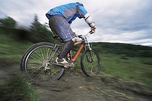 Man outdoors on trails riding bicycle (selective focus)