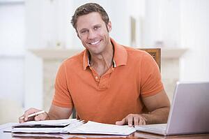 Man in dining room with laptop smiling