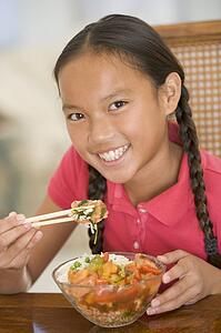 Young girl in dining room eating chinese food smiling