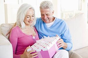 Husband giving wife gift in living room smiling