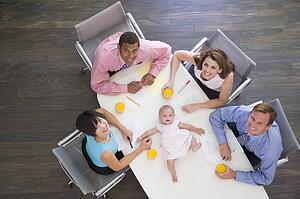 Four businesspeople in boardroom with a baby lying on the table