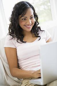 Woman in living room with laptop smiling (high key/selective focus)