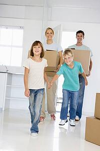 Family with boxes moving into new home smiling