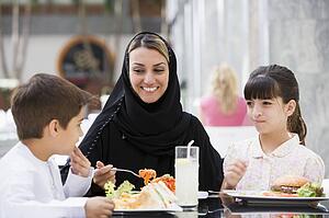 Woman and two young children at restaurant eating and smiling (selective focus)