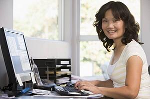 Woman in home office using computer and smiling