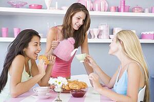 Three young woman sitting at a table having tea and a snack