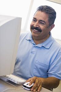 Man at computer smiling and looking at monitor (high key)