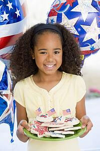 Young girl on fourth of July with balloons and cookies smiling