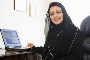 Woman in office with laptop smiling (high key/selective focus)