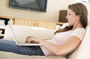 Woman in living room using laptop smiling
