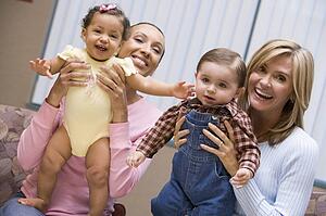 Two mothers holding two IVF children smiling