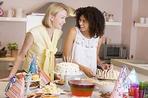 Two women at party getting sandwiches smiling