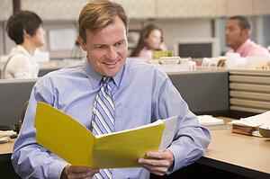 Businessman in cubicle with folder smiling