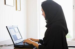 Woman in office with laptop smiling (high key/selective focus)
