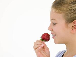 Young girl eating strawberry smiling