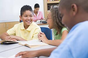 Students in class reading with teacher in background (selective focus)