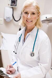 Middle Aged Female Doctor Writing On A Clipboard