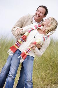 Couple standing on beach smiling