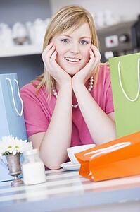 Young woman sitting at a table taking a break from shopping